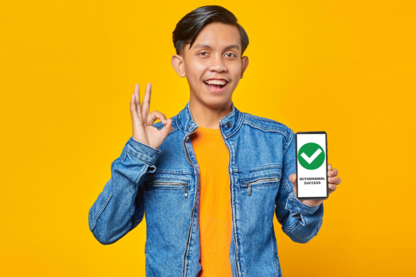 portrait-of-young-asian-man-holding-smartphone-and-showing-ok-sign-over-yellow-background